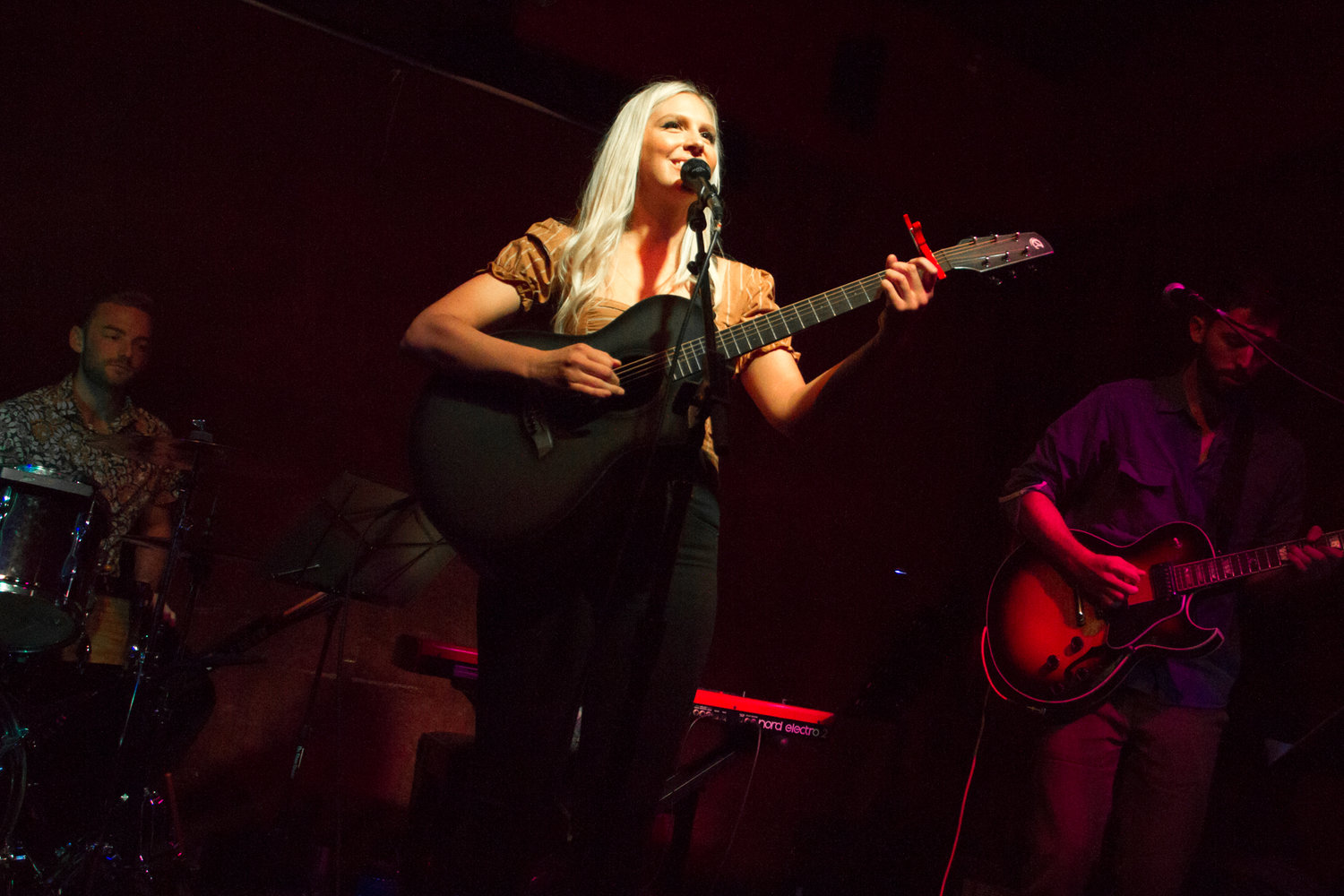 Christine performing with band, warm lighting