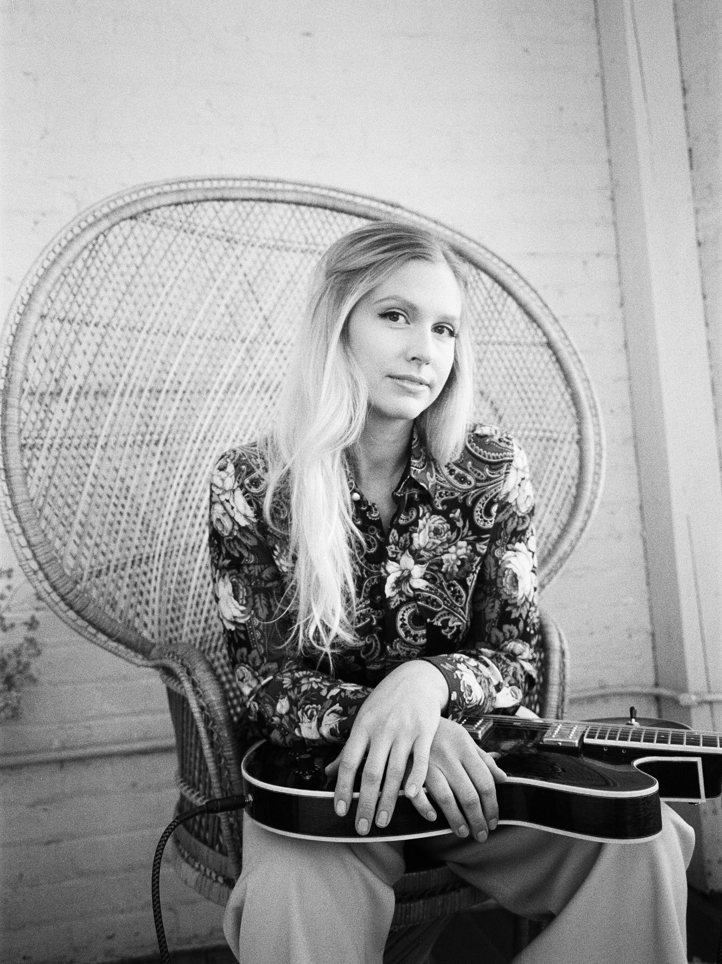 Portrait of Christine in a wicker chair with guitar