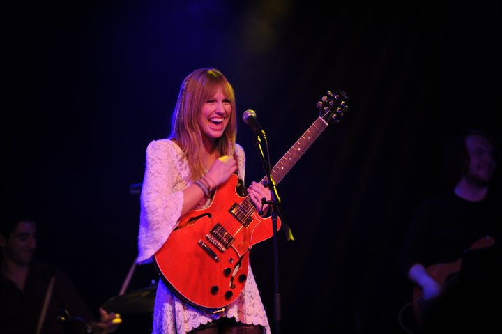 Christine on stage with a red electric guitar