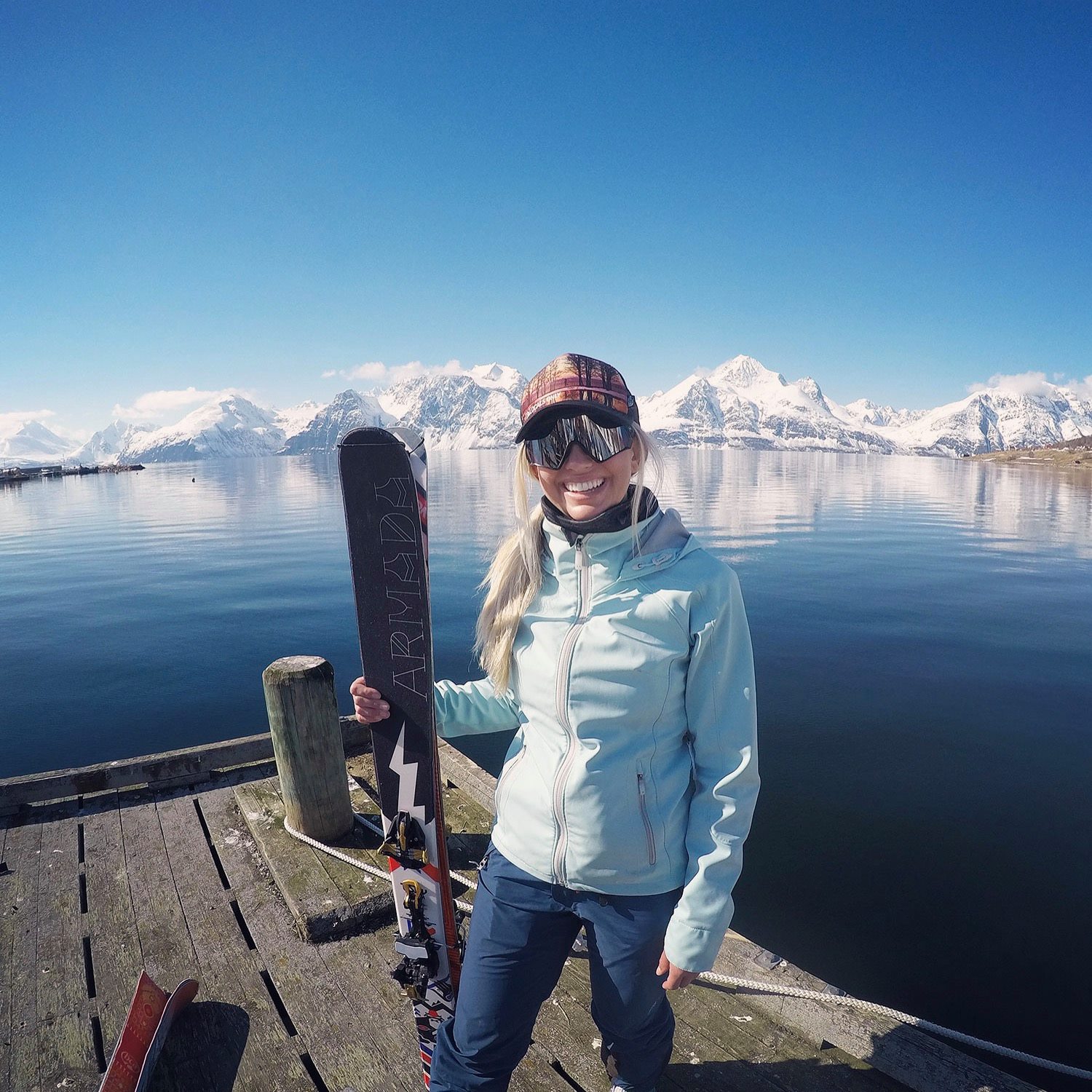 Christine with skis on a dock in front of arctic mountains